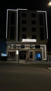 duży budynek z oświetloną fasadą w nocy w obiekcie سيفن سون للأجنحة الفندقية w mieście Abha