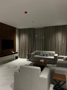 سيفن سون للأجنحة الفندقية في أبها: غرفة معيشة مع أريكة وتلفزيون