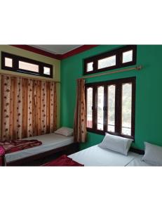 una camera verde con due letti e due finestre di Raj Palace, Uttarkashi a Uttarkāshi