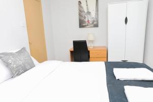 a white bedroom with a bed and a chair at Entire 3 bedroom house, 3 toilets, 2 baths, sleep 9 with free parking in Thamesmead