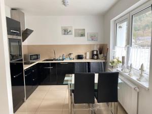 a kitchen with black cabinets and a glass table at Haus Sonnentag in Bad Bertrich