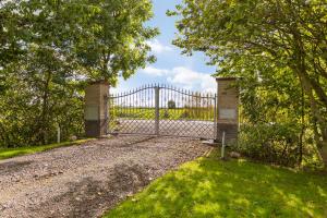 a gate in the middle of a field with trees at B&B Hoptille in Hijlaard