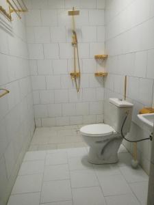 a white bathroom with a toilet and a sink at Le BASTA in Ouagadougou