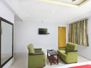 Sai Golden Rooms في تيروباتي: غرفة معيشة مع كرسيين وتلفزيون