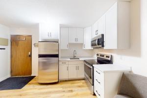 a kitchen with white cabinets and a stainless steel refrigerator at Snow Ghost Inn, Unit #311 in Big White