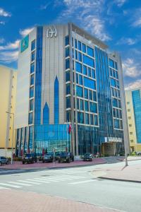 un gran edificio con coches estacionados frente a él en A&H Hotel Apartment, en Doha
