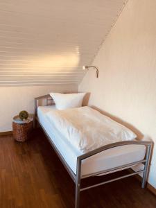 una cama con sábanas blancas y una lámpara en una habitación en Ferienwohnung im schönen Westerwald, 