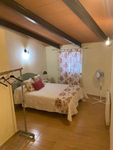 um quarto com uma cama, uma ventoinha e uma janela em Buhardilla Rústica Mirando a Santa Catalina em Jerez de los Caballeros