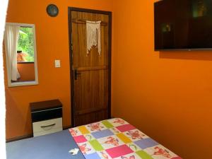 sypialnia z pomarańczowym pokojem z łóżkiem i drzwiami w obiekcie Casa em Lumiar - Barulhinho do Rio w mieście Lumiar