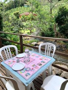 una mesa con una copa de vino y dos sillas en Casa em Lumiar - Barulhinho do Rio en Lumiar