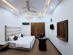 Schlafzimmer mit einem Bett und einem Deckenventilator in der Unterkunft Green Land Hotel Lahore in Lahore