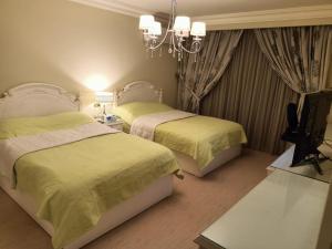 een slaapkamer met 2 bedden, een televisie en een kroonluchter bij Luxury Apartment In Massaken Sheraton near Cairo Int'l Airport in Caïro