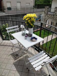 - une table et des chaises blanches sur un balcon fleuri dans l'établissement RIFUGIO DEL LAGO, à Paratico
