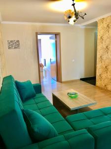 ein Wohnzimmer mit einem grünen Sofa und einem Tisch in der Unterkunft Homee in Tbilisi City