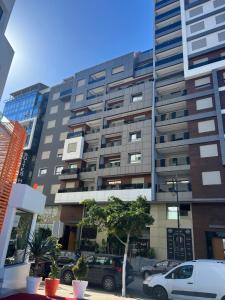 Un edificio alto con coches aparcados delante. en Le LUXE EN BORD DE MER, en Tánger