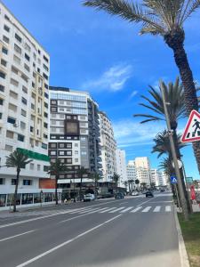una calle de la ciudad con palmeras y edificios en MODERNE, LUXUEUX et FRONT DE MER, en Tánger 3 fotos más