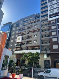 Un gran edificio con coches aparcados delante. en MODERNE, LUXUEUX et FRONT DE MER, en Tánger