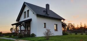 uma casa branca com um telhado preto em Apartamenty i Domki Mierzeja em Sztutowo