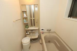 a bathroom with a tub and a toilet and a sink at Guest House Kubo Homes Matsu in Osaka