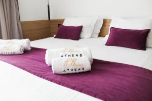 two beds with white and purple pillows on them at Athens Lodge by Athens Prime Hotels in Athens