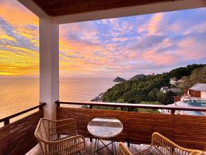 a balcony with a table and chairs overlooking the ocean at The AVA Resort Koh Tao in Ko Tao