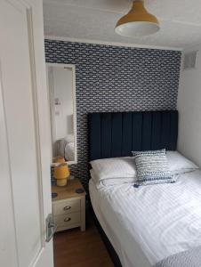um quarto com uma cama com uma cabeceira azul e um espelho em Savannah-by-the-sea em Bridlington