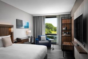um quarto de hotel com uma cama e uma cadeira e uma televisão em Courtyard by Marriott Amsterdam Airport em Hoofddorp