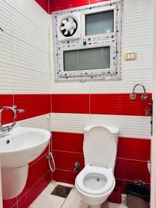 a red and white bathroom with a toilet and a sink at 91 الميرلاند الدور 7 in Cairo