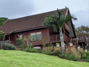 a wooden house with a palm tree in front of it at Eagles Call in Port Edward