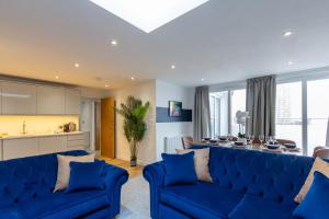 a living room with blue couches and a table at Regent Grand Penthouse in Brighton & Hove