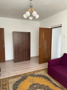 a living room with a purple couch and wooden cabinets at Velovan Apartment in Craiova