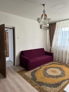 sala de estar con sofá púrpura y alfombra en Velovan Apartment, en Craiova