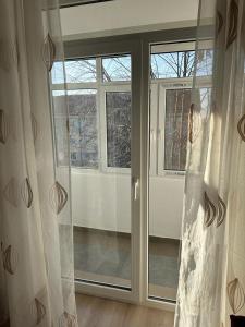 Habitación con puertas correderas de cristal y ventana. en Velovan Apartment en Craiova