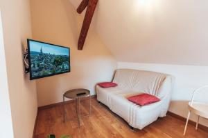 uma sala de estar com um sofá branco e uma televisão na parede em Aux Cerfs des Vignes - L'annexe em Scherwiller