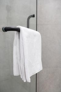 toalla blanca colgada en un toallero en una ducha en Стильный уголок рядом с EXPO - Современный Комфорт en Prigorodnyy