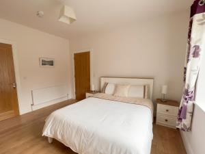 a bedroom with a white bed and a wooden floor at Woodview Lodge in Trim