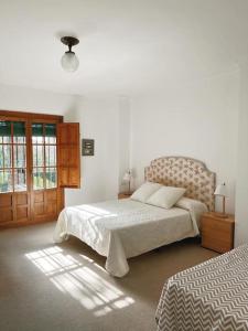 a white bedroom with a bed and a window at Villa a los pies de la Alhambra in Granada