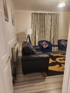 2-bedroom flat in Cutty-Sark, Greenwich ! في لندن: غرفة معيشة مع أريكة جلدية سوداء وكراسي زرقاء