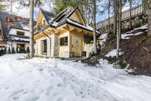 uma casa de madeira na neve com uma entrada em Chatka Kryjówka em Kościelisko