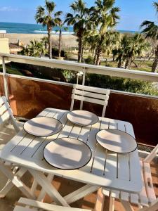 een witte tafel en stoelen op een balkon met uitzicht op het strand bij Les Capitelles 97 - Studio vue mer - residence avec pisicne in Saint-Cyprien