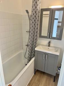 een badkamer met een wastafel, een bad en een spiegel bij Les Capitelles 97 - Studio vue mer - residence avec pisicne in Saint-Cyprien