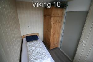 een kleine slaapkamer met een bed en een houten kast bij Appartementen Zuiderstrand in Westkapelle