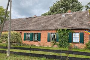 a red brick house with green shutters and a fence at Landhaus Lange3 Moderne Kunst in Poitendorf