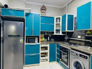 a kitchen with blue cabinets and a washer and dryer at 91 الميرلاند الدور 8 in Cairo