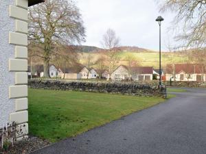 a stone retaining wall next to a street with houses at Coiltie Cottage in Drumnadrochit