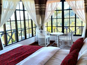 a bedroom with a bed and two chairs and windows at Chez Allen in Nuwara Eliya