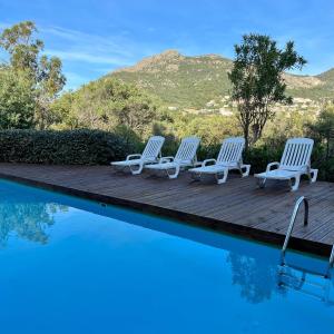 a group of chairs sitting on a wooden deck next to a swimming pool at Piana in Lumio