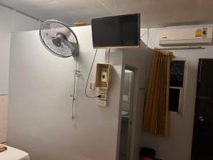 a room with a fan and a tv on the wall at Metro Palace in Satun