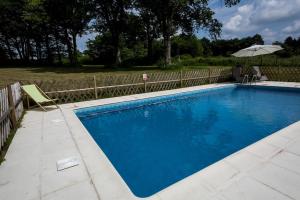 uma piscina azul com um guarda-sol e uma cadeira em L'Amelia em Cromac