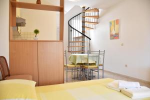a dining room with a table and a spiral staircase at Apartments Stone Tučepi in Tučepi